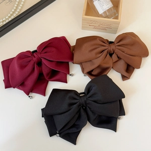 Détail de trois barrettes à cheveux en satin multicouches bordeaux, marron et noir