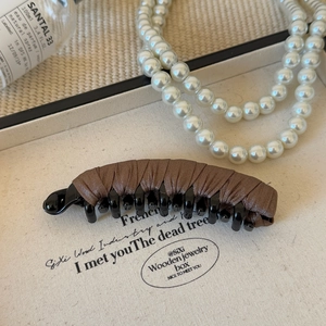 Detailed view of a brown fabric wrapped banana clip on a vintage decorative tray