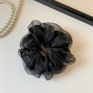 Close-up of elegant black organza scrunchie featuring delicate sparkles and mesh texture