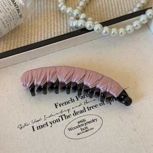 Detail of elegant dusty pink fabric wrapped banana clip on a white textured tray