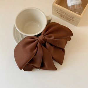 Détail d'une grande pince à cheveux nœud en satin marron avec perle en cristal sur tasse