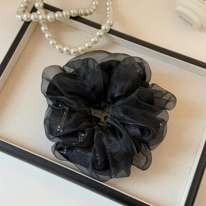 Detail of black pleated organza scrunchie with silver glitter stripes on display