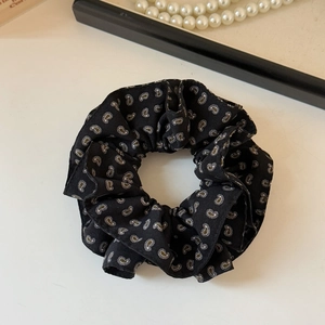 Vue détaillée d'un chouchou noir à motif paisley avec une texture plissée douce