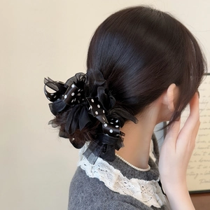 Elegant black polka dot bow scrunchie with lace mesh on model's low bun hairstyle