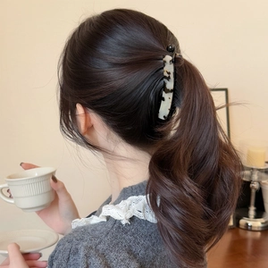 Detail showing marble textured acetate banana hair clip holding a low ponytail for women