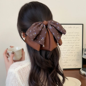 Elegant floral satin bow hair claw clip with crystal pendants on brown wavy hair