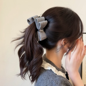 Detail of grey knitted bow hair clip with crystal flower embellishment on model