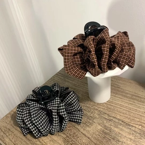 Detailed view of houndstooth fabric wrapped hair claw clips on a wooden stand