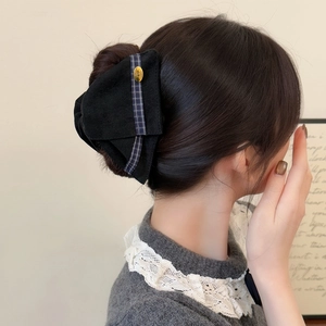 Détail d'une pince à cheveux en velours noir élégante avec emblème doré sur femme