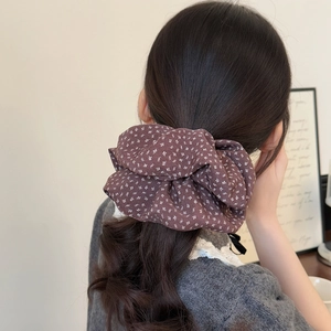 Floral print hair scrunchie in deep brown fabric shown on a low ponytail hairstyle