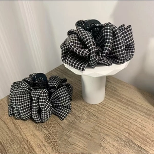 Two-piece set of large pleated houndstooth hair claw clips on a wooden tabletop