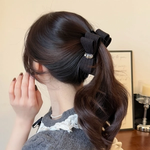 Elegant black knit bow hair clip with sparkling rhinestones worn on wavy hair ponytail
