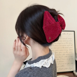 Detail of elegant wine red velvet bow hair clip with subtle gold shimmer texture