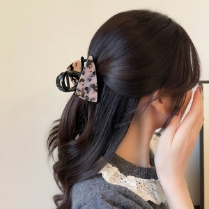 Pink and black tortoiseshell acetate hair claw clip with golden B accent on female model