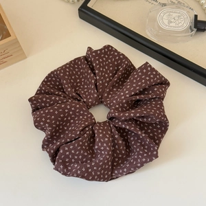 Detailed texture of brown floral scrunchie with white patterns on a wooden vanity