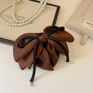 Détail d'un nœud papillon en satin marron avec liseré noir et perles blanches suspendues