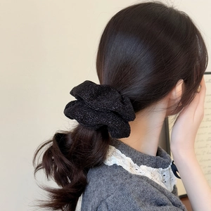 Close-up of black knit scrunchie with silver glitter texture on a low ponytail