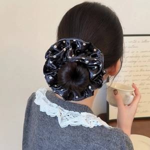 Chic black and white polka dot satin oversized scrunchie styled on a messy bun