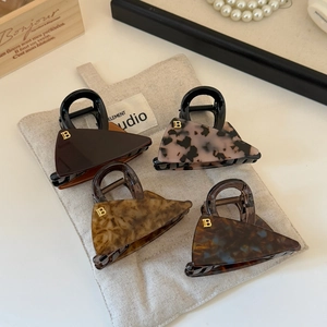 Set of four stylish triangle acetate hair claws with gold B letter on fabric bag