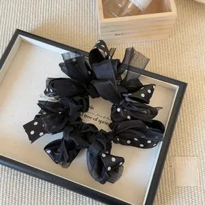 Detail of elegant black polka dot chiffon hair scrunchie with bow ribbon and soft texture