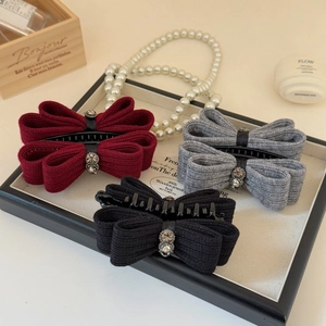 Detailed close-up of bow hair clips with rhinestones in burgundy, grey, and black