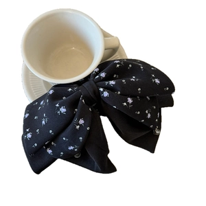 Elegant black satin hair claw clip with lilac floral pattern and double bow design