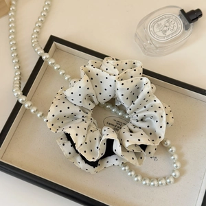 Detailed view of polka dot silk scrunchie with layered fabric on jewelry tray