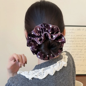 Polka dot velvet scrunchie in deep purple on a bun hair style for a vintage look
