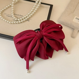 Gros plan sur la pince à cheveux en satin bordeaux avec détails de perles élégantes