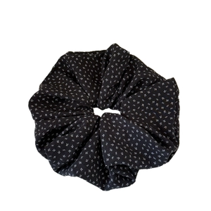 Elegant black scrunchie with tiny white floral pattern in a ruffled fabric design