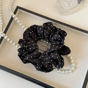 Detail view of a satin polka dot scrunchie on a decorative tray with elegant pearls