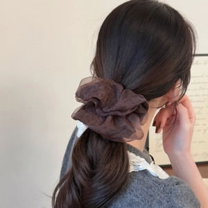 Brown leopard mesh scrunchie with double-layer design worn by a model in a cozy setting