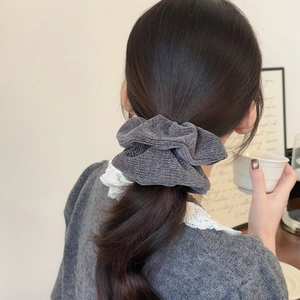 Elegant dark grey knit scrunchie with silver glitter worn on a ponytail hair