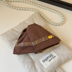 Détail de la pince à cheveux en tissu marron avec ruban écossais et badge cerise doré