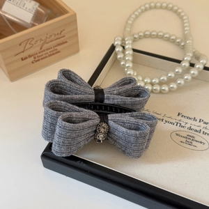 Close-up of grey glitter ribbon bow hair clip with rhinestone flower and pearls