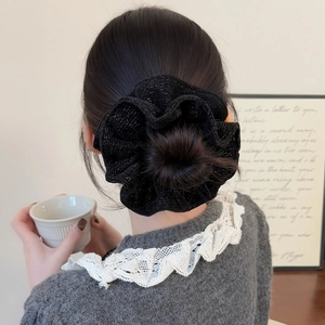 Detail of black large scrunchie with silver glitter texture worn on a bun hairstyle