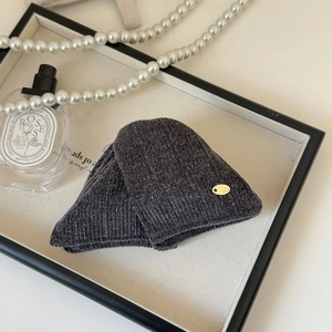 Detail of dark grey knit fabric with silver sparkles and a gold decorative clasp