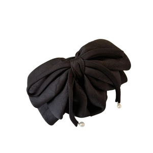 Barrette à cheveux avec grand nœud noir en ruban et perles blanches sur fond blanc