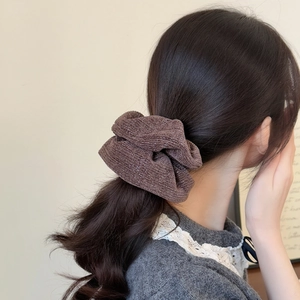 Close-up of a dark coffee knitted scrunchie with subtle shimmer on a model's ponytail