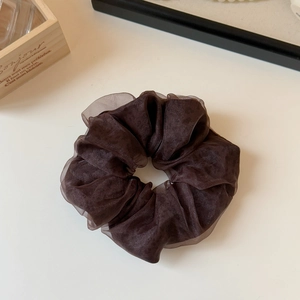 Detailed texture of dark brown mesh organza scrunchie with layered fabric design