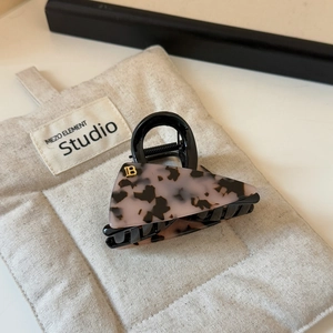 Detailed macro view of acetate triangular hair claw clip with leopard pattern and gold B logo