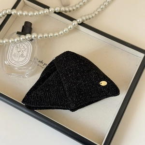 Detail of luxury black knit hair clip with silver glitter and gold metal plate