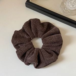 Detailed texture of dark brown knit scrunchie with metallic threads and fine pleats