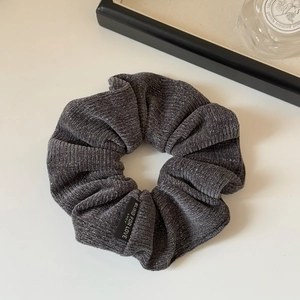 Detailed macro view of charcoal grey knit scrunchie with shiny metallic thread texture