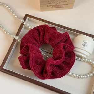 Detail of dark red shimmering hair scrunchie with metallic glitter silk texture