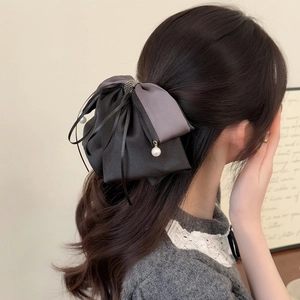 Detail of elegant oversized bow hair clip with satin fabric and dangling pearls