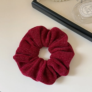 Close-up of wine red knit scrunchie with silver metallic thread and rich pleats
