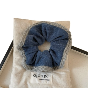 Deep blue denim scrunchie with grey crochet lace trim displayed on beige canvas