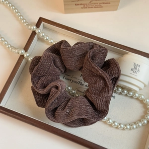 Detail of dark brown knit scrunchie with silver glitter thread on a wooden tray
