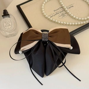 Detail of a tri-color satin bow hair clip with black rhinestones and pearl ribbons